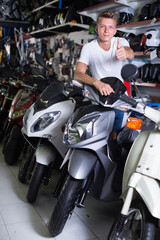 Fototapeta na wymiar ...Smiling man sitting on the motorbike in the motorcycle shop