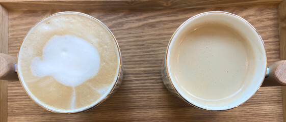 Top view of two cups of cappuccino on wooden table