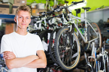 Fototapeta na wymiar Portrait of young attractive male standing near the cycle in the shop