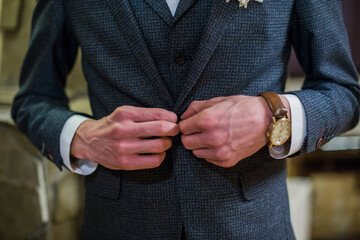 groom puts on a suit jacket in the room