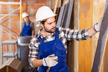 Two professional builders insulate walls inside the house. High quality photo