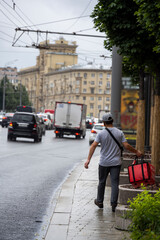 courier with a red bag walks along the road