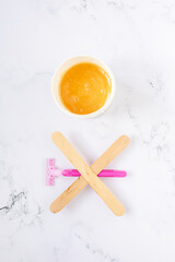 depilation and beauty concept - sugar paste or wax honey for hair removing with wooden waxing spatula sticks