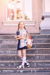 Obraz premium Young schoolgirl with backpack. Lifestyle going to classroom. Outdoor autumn park. Children learn smart. Street student. Happy preschool kid. Back to school. Near building