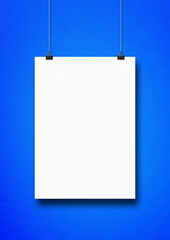 White poster hanging on a blue wall with clips