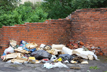 A pile of trash against a broken red brick wall