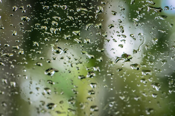Rainy Day Water Droplets on Window with out of focus background Gloomy Day Wallpaper with Green Natural Backdrop