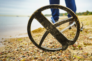 Man with metal detector on sea beach