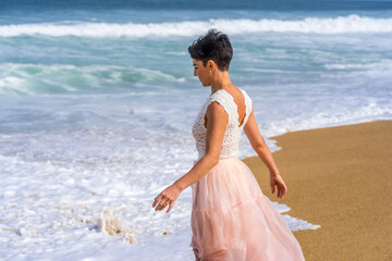 Fototapeta na wymiar Young woman walking on the Atlantic ocean beach waves. Beautiful model. Soft background. High quality photo