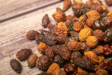 Dried rosehip fruits scattered on a wooden background. Close up.