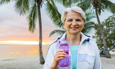 fitness, sport and healthy lifestyle concept - happy smiling sporty senior woman with bottle of...