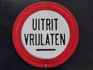 Mandatory sign with a red border, black text on a white background with the commandment in Dutch language   Leave the exit