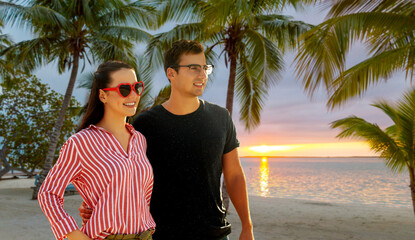 travel, tourism and vacation concept - happy couple hugging over tropical beach background in...