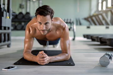 Fototapeta na wymiar Male athlete in plank pose exercising at health club.