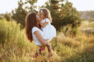 Moms and daughter in nature kiss in the summer walk