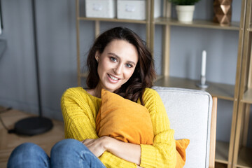 Obraz premium Young woman on the couch with a pillow in her hands at home.^