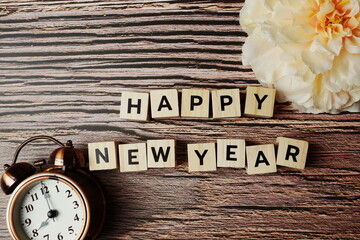 Happy New Year alphabet letter with alarm clock on wooden background