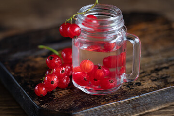 Homemade liqueur in shot glass with red current berries on the table