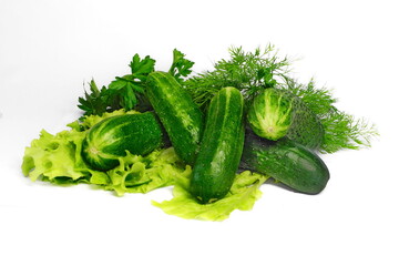 Cucumbers and bunches of greens on white isolated background