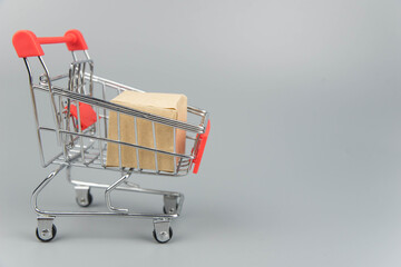Shopping cart with purchases - packages and boxes on trendy gray background with copy space...