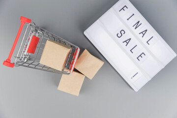 Shopping cart with purchases - packages and boxes on trendy gray background with copy space isolated. Online shopping and sale concept.