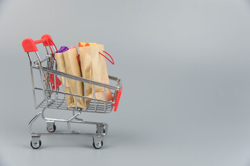 Shopping cart with purchases - packages and boxes on trendy gray background with copy space...