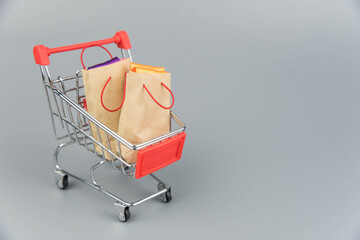 Shopping cart with purchases - packages and boxes on trendy gray background with copy space...
