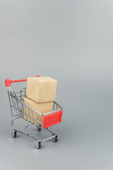 Shopping cart with purchases - packages and boxes on trendy gray background with copy space...