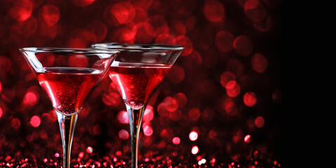 Two martini glasses in front of red bokeh background. Luxury cocktail drink in restaurant bar with...