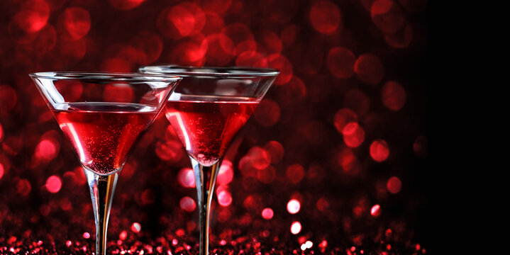 Two martini glasses in front of red bokeh background. Luxury cocktail drink in restaurant bar with night lights blur