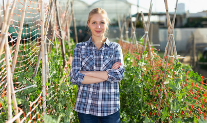Portrait of satisfied woman gardener standing in homestead outdoors