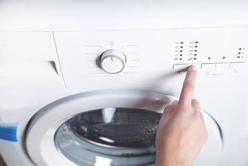 Girl hand pressing button on washing machine.