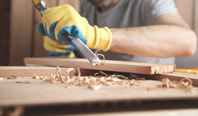 Carpenter using chisel into wooden plank.