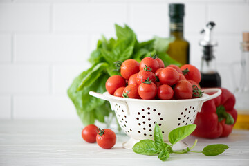 small tomatoes in a colander with basil and spices