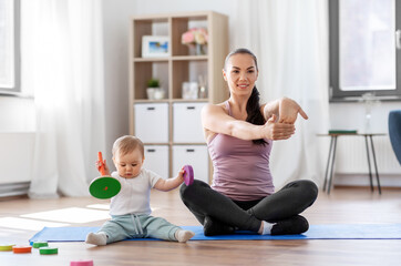family, sport and motherhood concept - happy smiling mother exercising on mat and little baby...