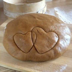 Brown gingerbread dough. It's on the table. Cut out two forms of hearts.