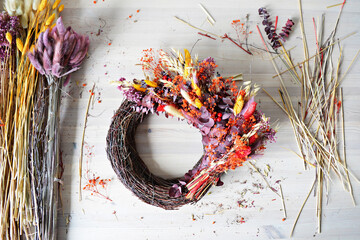 Festive fall wreath and colorful dried flowers on wooden desk