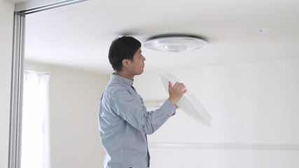 照明器具を取り付ける男性