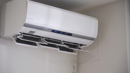 エアコンの電源をつける女性