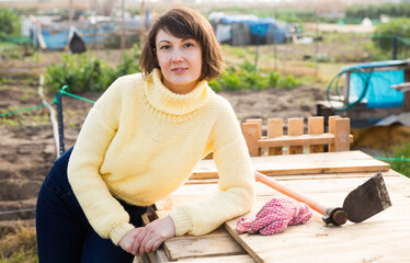 Portrait of pensive young woman resting in her homestead during gardening