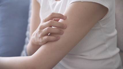 腕を掻いている若い女性	