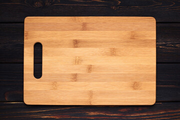 Multifunctional wooden cutting board for bread or steak serve. Top view on wooden kitchen table. Copy space 