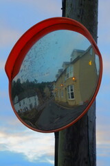 Traffic mirror on the street in village of Beer, Devon at dawn