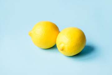 Two ripe lemons on a blue background. Minimal summer concept.
