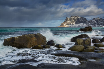 Fototapeta na wymiar A wave breaks on the rocks on the rocky seashore