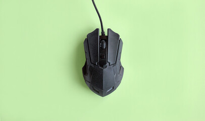 Matte modern black gaming mouse with buttons on a light green background.