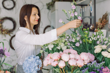 Beautiful female florist working in her flower shop arranging a bouquet. Small floral business owner. Female power startup concept.