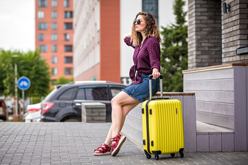 girl with a suitcase on the street. Girl with a suitcase goes on vacation. Girl with a suitcase travels.