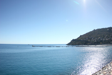 Alanya, TURKEY - August 10, 2013: Travel to Turkey. Rocks, wildlife of Turkey. Clear blue sky. The waves of the Mediterranean Sea. Water surface. Mountains and hills in the distance in the background.