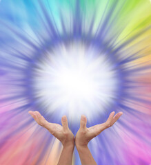 Extraordinary Multicoloured Energy Field Formation - female cupped hands reaching up to a bright white orb surrounded by rainbow colours radiating outwards with copy space 
